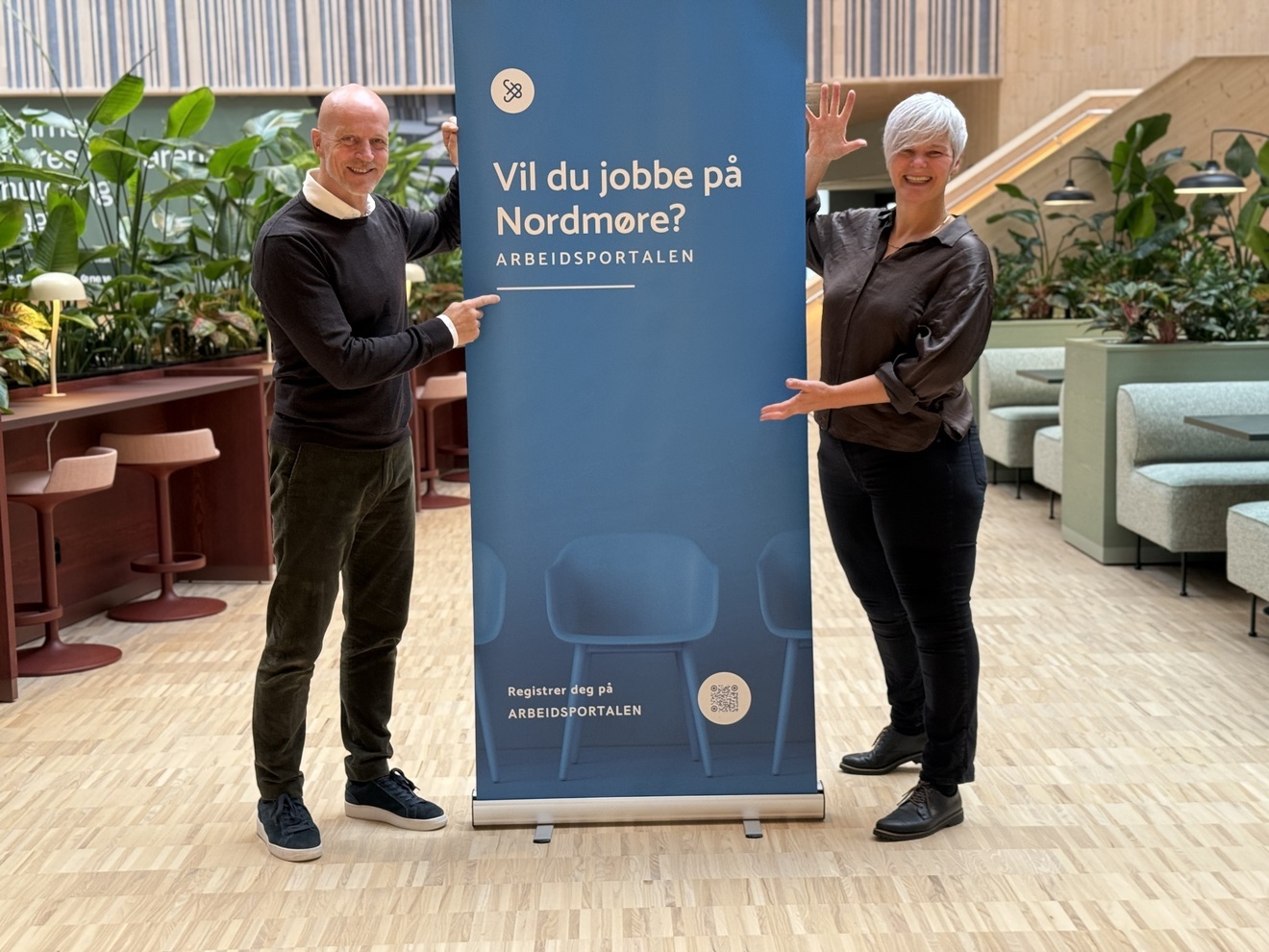 En mann og en kvinne står på hver sin side av en rollup med teksten 