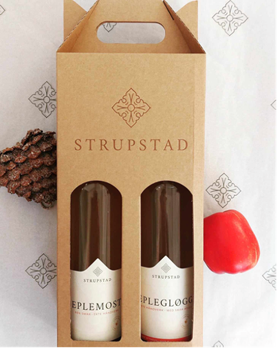 Bildet viser en brun gaveeske i papp med påskriften "Strupstad Sider" . Gjennom to hull i eksen skimtes to flasker med etiketter som også har påskriften "Strupstad". På den ene etiketten står det "eplemost" og på den andre står det "eplegløgg"